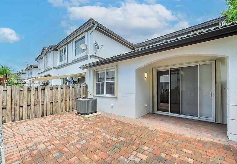 A paved patio sits beside a white house with a sliding glass door and fence — 7772 NW 114th Pl # 0, Doral FL 33178, DORAL, FL