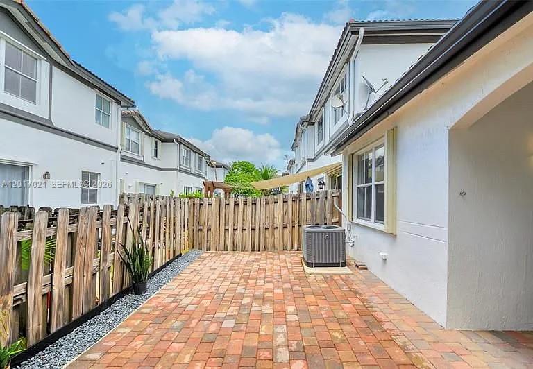 A brick patio sits between a white building and a wooden privacy fence — 7772 NW 114th Pl # 0, Doral FL 33178, DORAL, FL