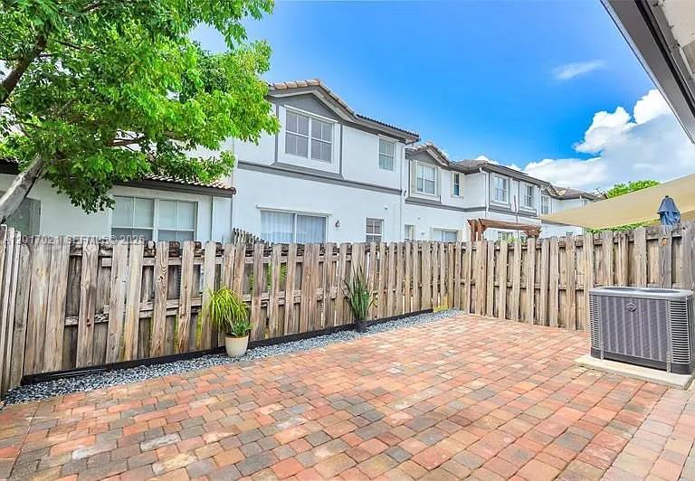 A paved patio features a wooden fence, a potted plant, and an outdoor air conditioning unit — 7772 NW 114th Pl # 0, Doral FL 33178, DORAL, FL