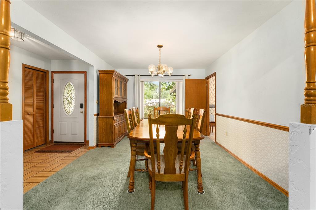 A dining room features a wooden table and chairs, a hutch, and green carpeting — 7027 NW 51ST TERRACE, GAINESVILLE, FL