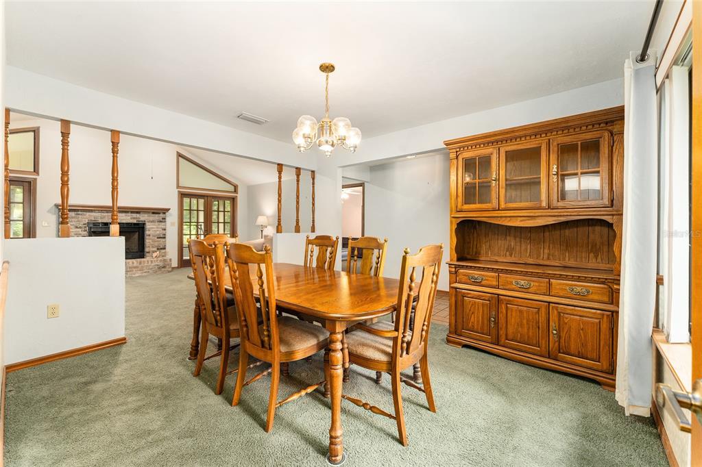 A dining room features a wooden table and hutch set on green carpeted flooring — 7027 NW 51ST TERRACE, GAINESVILLE, FL