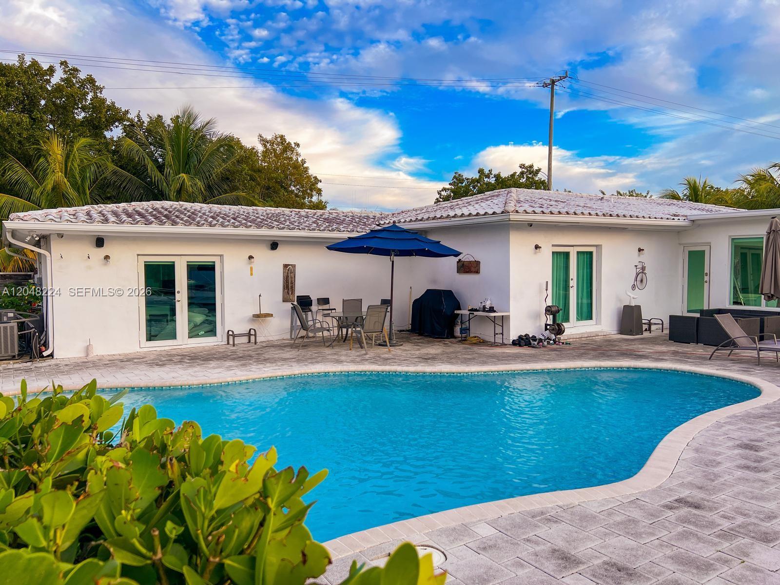 A white house with a tiled roof features a swimming pool and patio area — NORTH MIAMI, FL