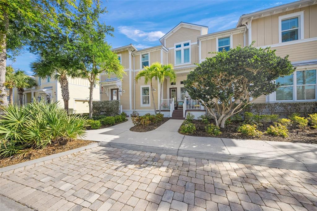 A two-story townhouse with light yellow siding and a paver driveway under a blue sky — 229 SAPPHIRE LAKE DRIVE UNIT 201, BRADENTON, FL