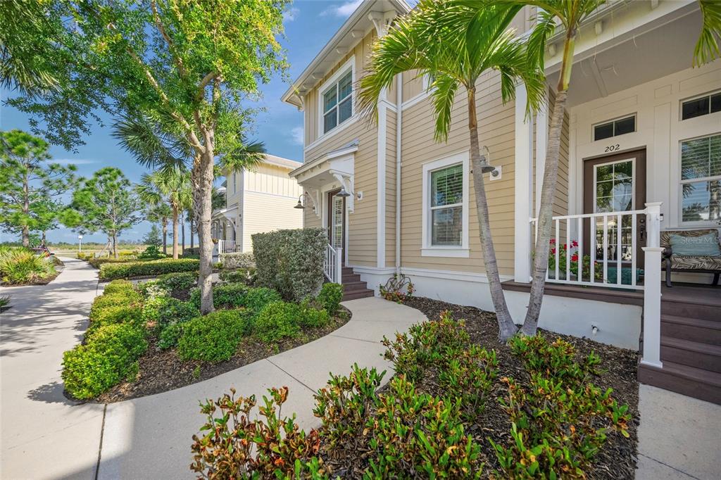 A two-story tan house with a front porch, palm trees, and a concrete walkway — 229 SAPPHIRE LAKE DRIVE UNIT 201, BRADENTON, FL