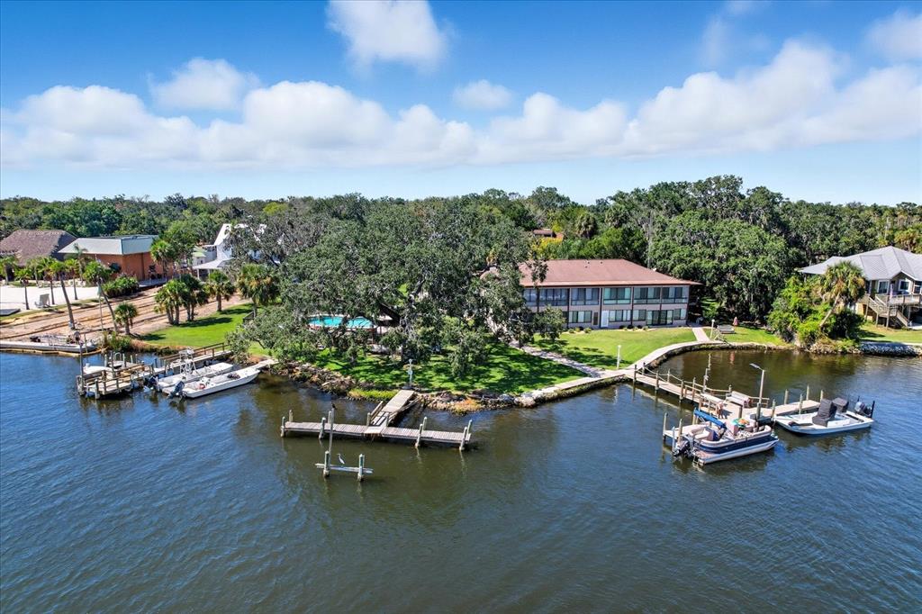 An aerial view shows a waterfront apartment building with docks, a pool, and mature trees — 5152 S SWIFTWATER WAY, HOMOSASSA, FL