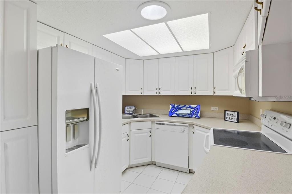 A kitchen features white cabinets, white appliances, a light-colored countertop, and a recessed ceiling light — 5152 S SWIFTWATER WAY, HOMOSASSA, FL