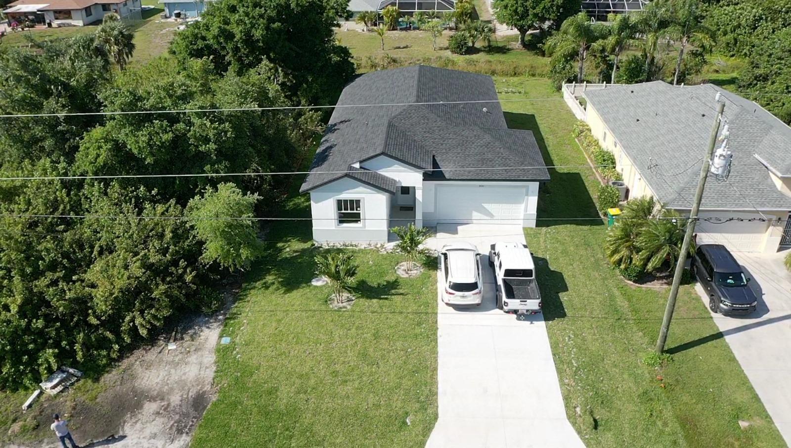 An aerial view shows a single-story house with a dark roof, white exterior, and driveway — 500 Sunset Road N, FL 33947, FL