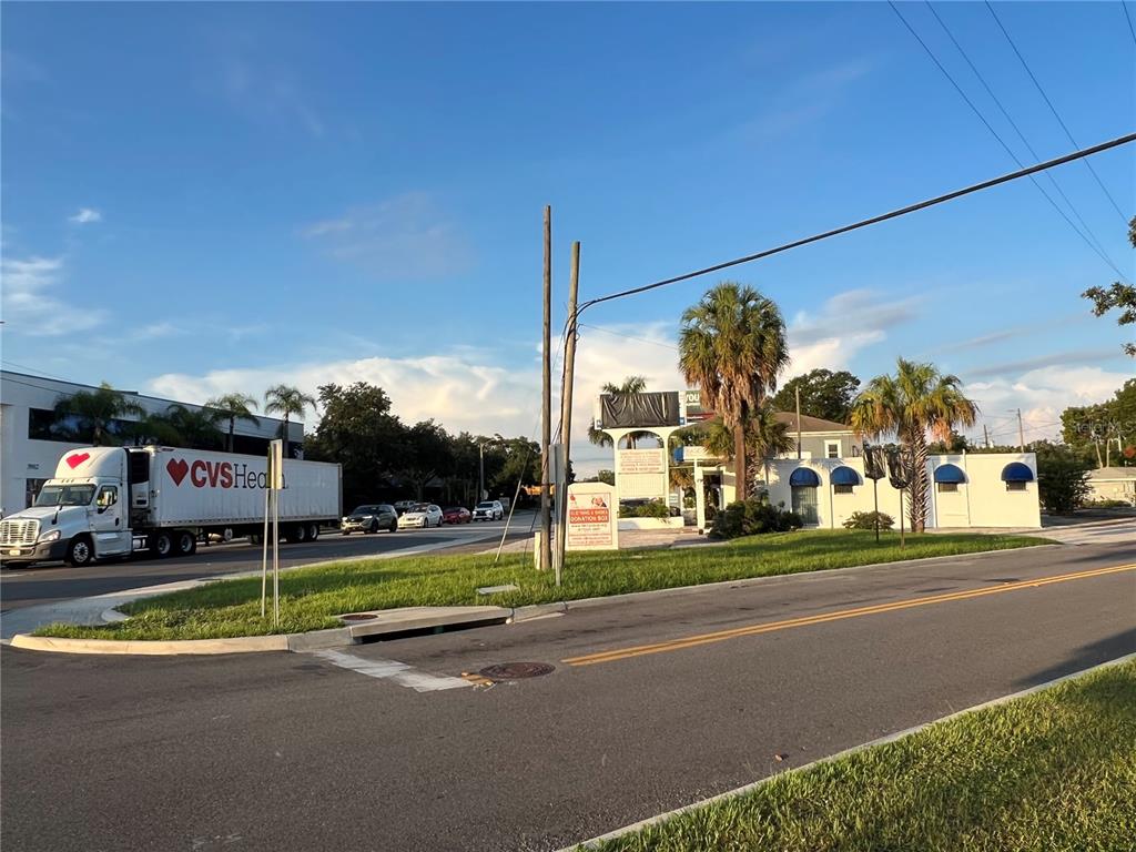 A CVS Health semi-truck drives past a commercial building with palm trees and a sign — 3901 HENDERSON BOULEVARD, TAMPA, FL