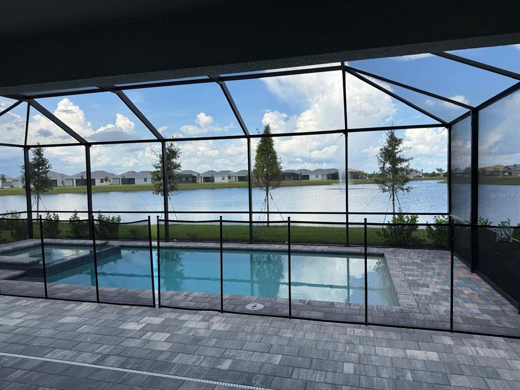 A screened-in patio features a swimming pool with a safety fence overlooking a lake — 7913 LAKES EDGE LANE, PORT CHARLOTTE, FL