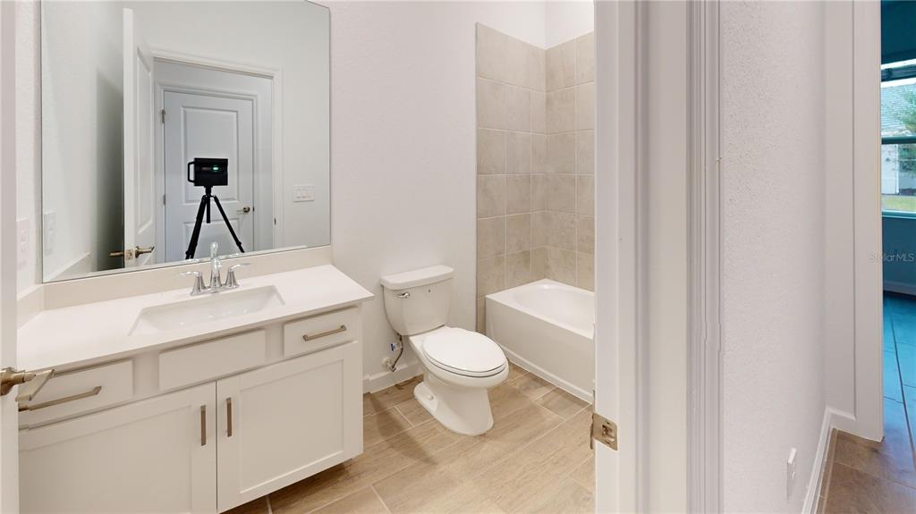 A bathroom features a white vanity, a toilet, and a bathtub with beige tile surround — 7913 LAKES EDGE LANE, PORT CHARLOTTE, FL