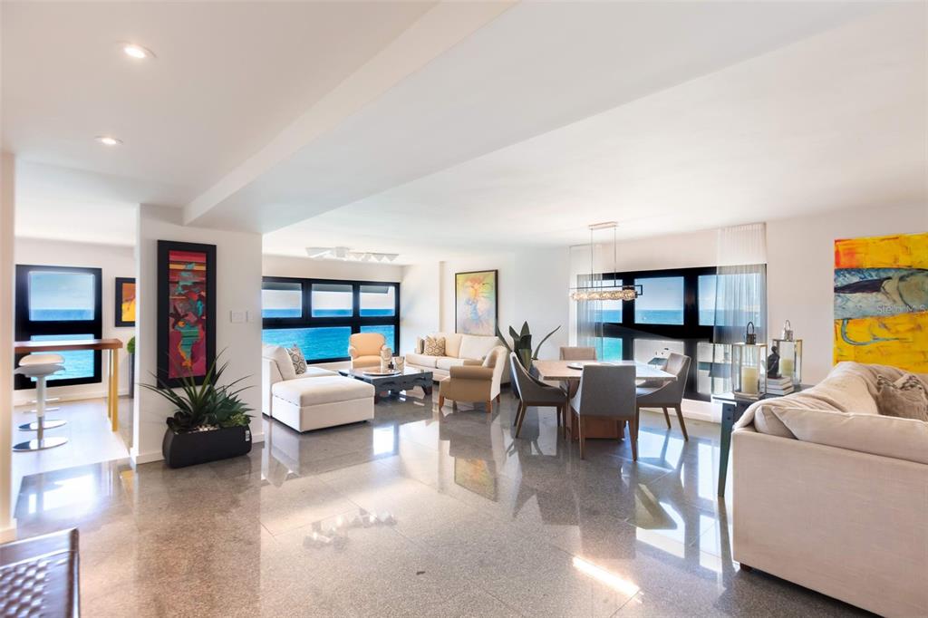 An open-concept living and dining area with glossy tile floors and floor-to-ceiling ocean views — 1507 ASHFORD AVE. AVENUE UNIT 1201, SAN JUAN, PR
