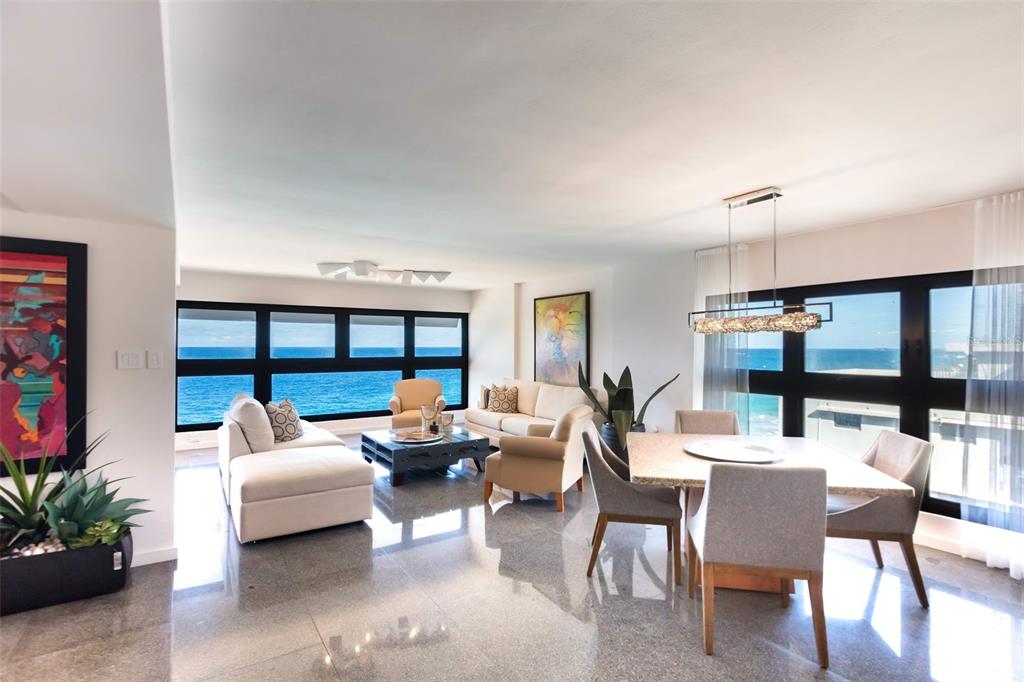 A bright, open-concept living and dining area features polished stone floors and expansive ocean views — 1507 ASHFORD AVE. AVENUE UNIT 1201, SAN JUAN, PR