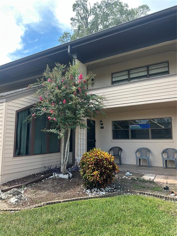 A two-story tan building features a front porch, a flowering tree, and a small shrub — 2415 NE 7TH STREET UNIT 2, OCALA, FL