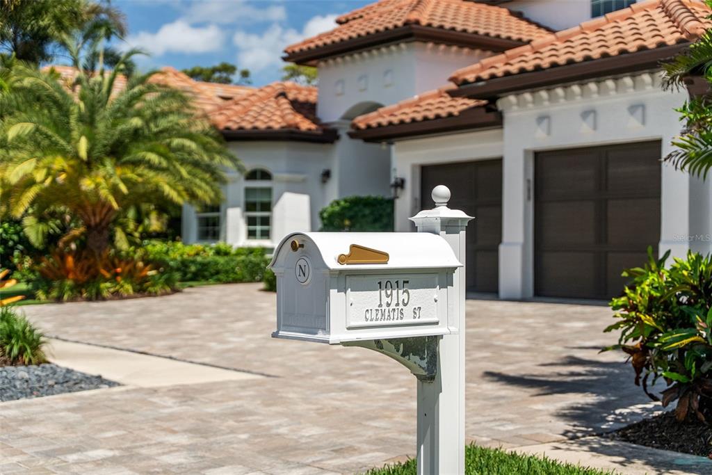 A white mailbox stands in the foreground of a house with a tiled roof — 1915 CLEMATIS STREET, SARASOTA, FL