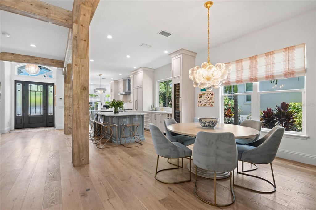 A dining area with a round table and blue chairs sits beside a modern kitchen — 1915 CLEMATIS STREET, SARASOTA, FL