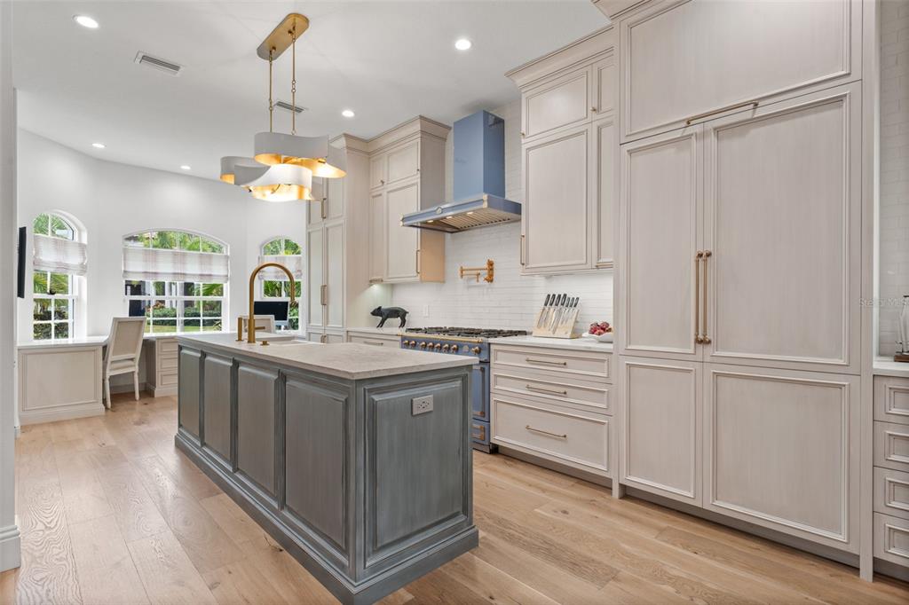 A kitchen features a blue range hood, a gray island, and light-colored cabinetry — 1915 CLEMATIS STREET, SARASOTA, FL
