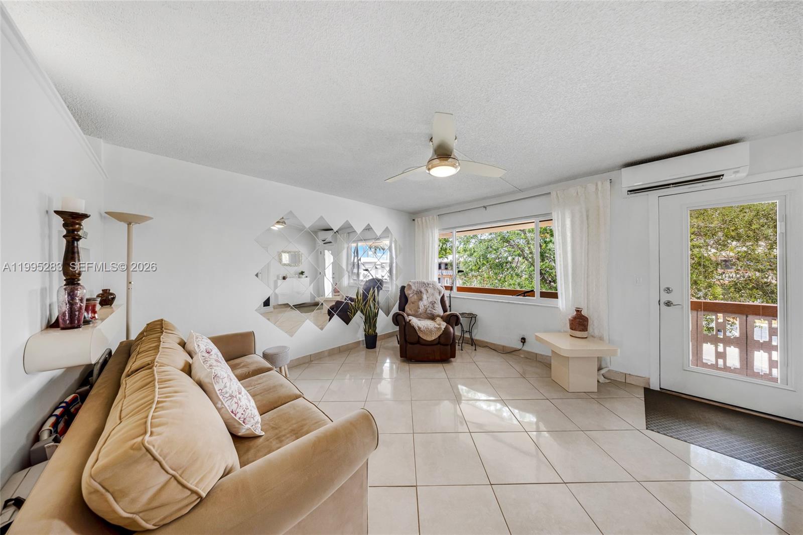 A living room features a beige sofa, tiled flooring, a ceiling fan, and mirrored wall decor — 1015 SW 11th Ave # 15K, Hallandale Beach FL 33009, HALLANDALE BEACH, FL