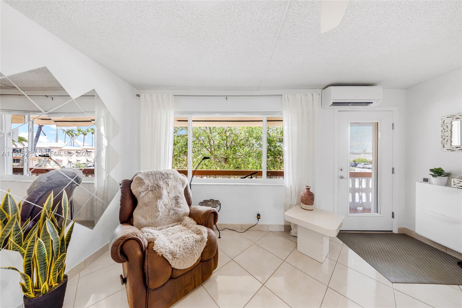 A living area features a brown leather recliner, tiled floors, a mirror, and a door — 1015 SW 11th Ave # 15K, Hallandale Beach FL 33009, HALLANDALE BEACH, FL