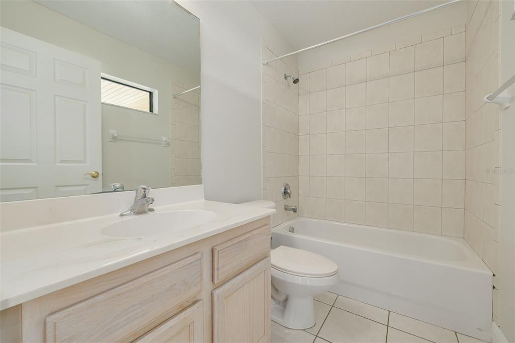 A bathroom features a vanity with a white countertop, a toilet, and a tiled tub — 616 YARDARM DRIVE UNIT 8, APOLLO BEACH, FL