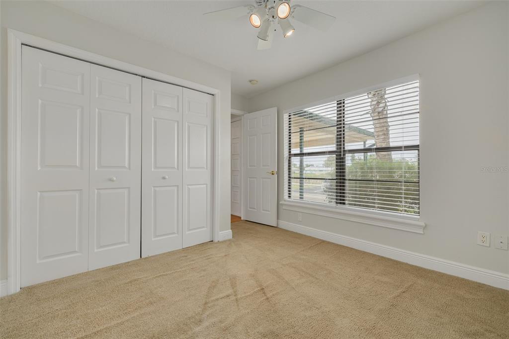 A bedroom with beige carpet, white walls, a ceiling fan, and a large window — 616 YARDARM DRIVE UNIT 8, APOLLO BEACH, FL