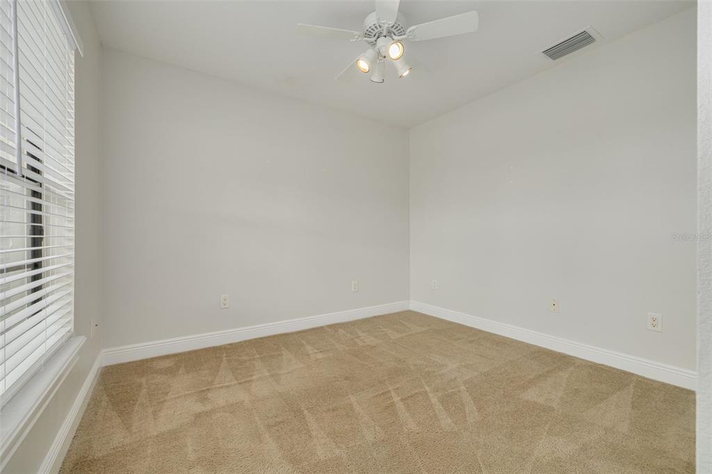 An empty bedroom features beige carpet, white walls, a ceiling fan, and a window with blinds — 616 YARDARM DRIVE UNIT 8, APOLLO BEACH, FL
