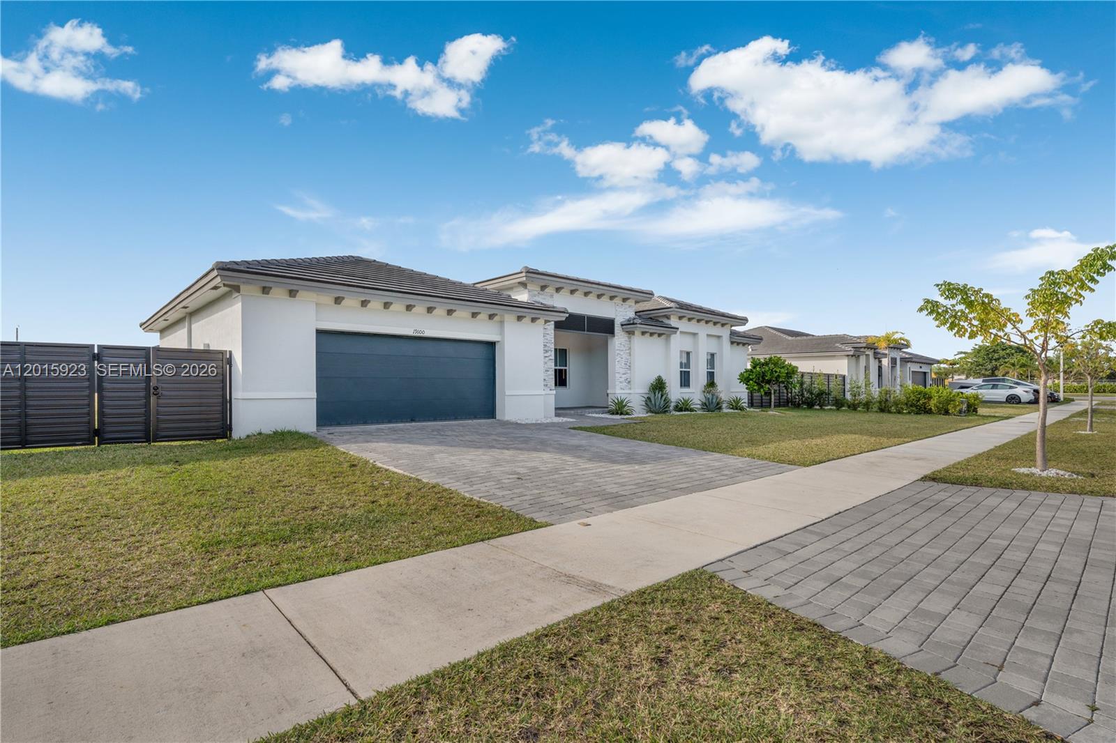 A modern single-story house features a dark garage door, white stucco walls, and stone accents — 19100 SW 132nd Pl, Miami FL 33177, MIAMI, FL