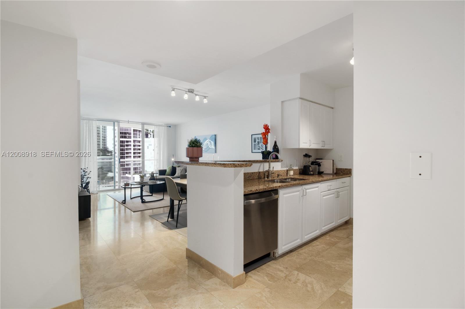 A kitchen with granite countertops and white cabinets opens into a bright living area — 1155 S Brickell Bay Dr # 805, Miami FL 33131, MIAMI, FL