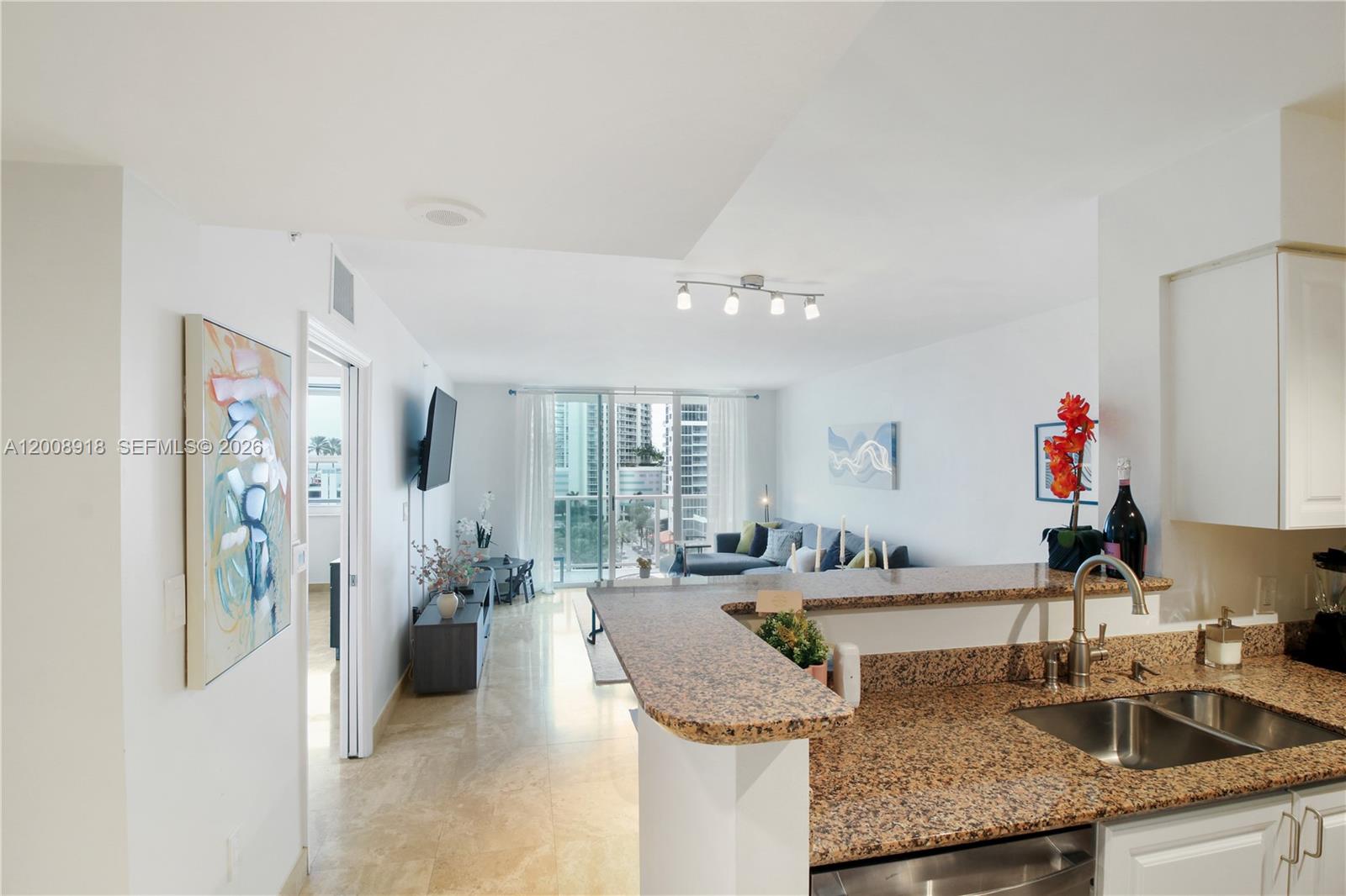 A kitchen with granite countertops overlooks a living area with a balcony and city views — 1155 S Brickell Bay Dr # 805, Miami FL 33131, MIAMI, FL