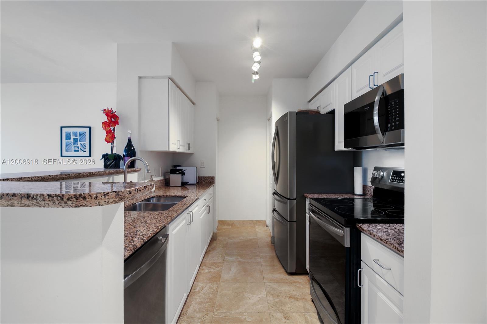 A galley kitchen features white cabinets, granite countertops, and stainless steel appliances — 1155 S Brickell Bay Dr # 805, Miami FL 33131, MIAMI, FL