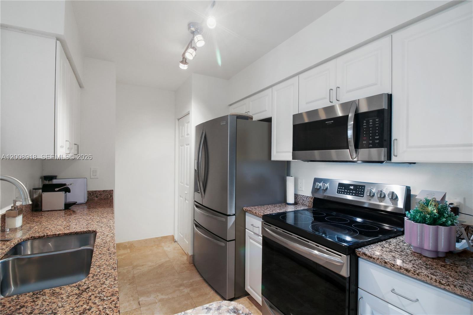 A kitchen features white cabinets, granite countertops, stainless steel appliances, and tile flooring — 1155 S Brickell Bay Dr # 805, Miami FL 33131, MIAMI, FL