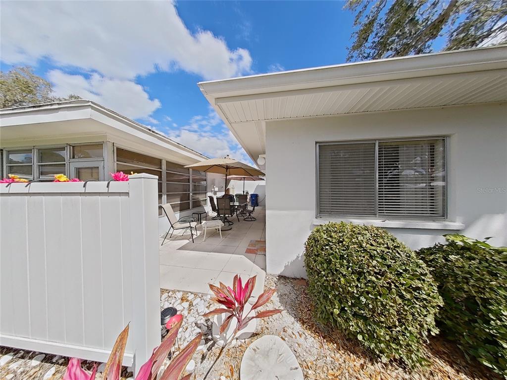 A patio area with outdoor furniture sits between two white exterior walls of a house — 1845 VERA PLACE UNIT 29, SARASOTA, FL