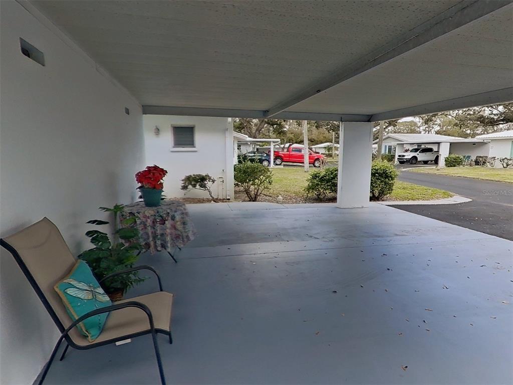 A covered carport with a concrete floor, a chair, and a small table — 1845 VERA PLACE UNIT 29, SARASOTA, FL