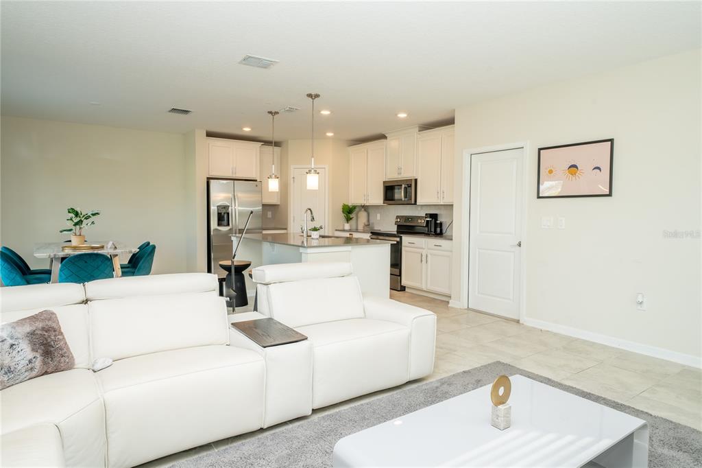 A white sofa sits in the foreground of an open-concept kitchen and dining area — 2831 ALDER BERRY BOULEVARD, OCOEE, FL