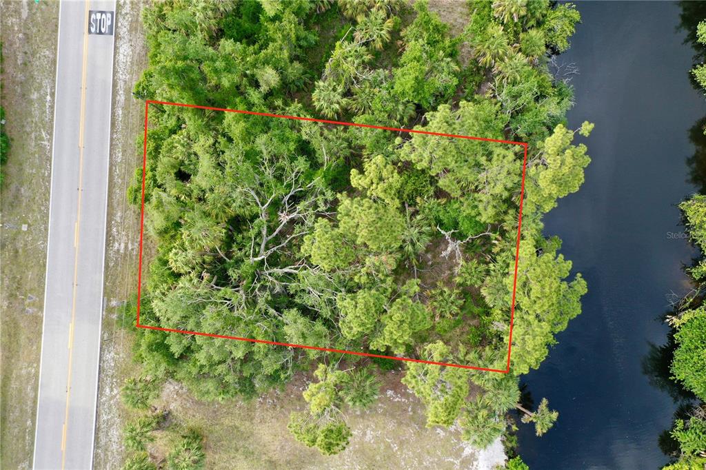 An aerial view shows a rectangular plot of land bordered by a road and water — 3020 COMO STREET, PORT CHARLOTTE, FL