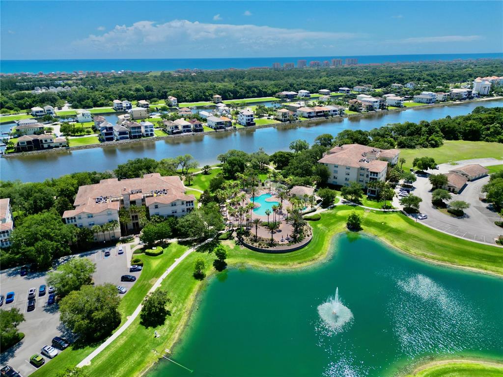 An aerial view shows a residential complex with a pool, pond, and surrounding landscape — 85 RIVERVIEW BEND S UNIT 1532, PALM COAST, FL