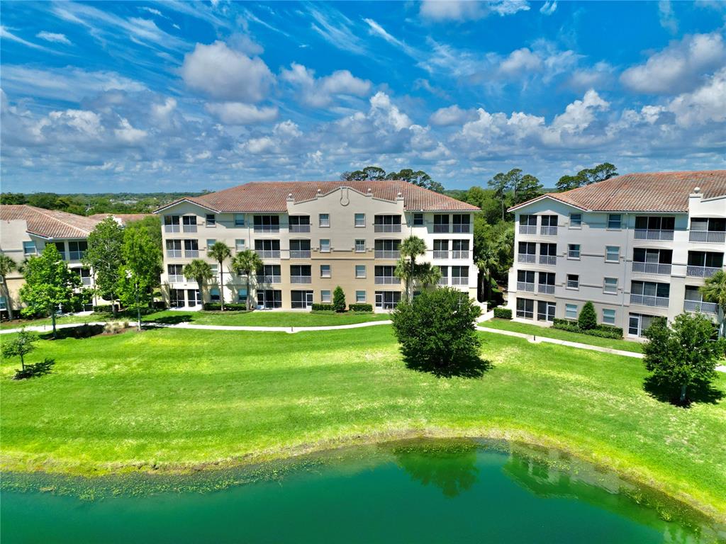 An aerial view shows two multi-story apartment buildings overlooking a green lawn and a pond — 85 RIVERVIEW BEND S UNIT 1532, PALM COAST, FL