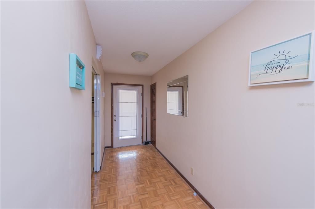 A hallway with parquet flooring leads to a living room featuring a brick fireplace — 34 OAKMONT CIRCLE, ORMOND BEACH, FL