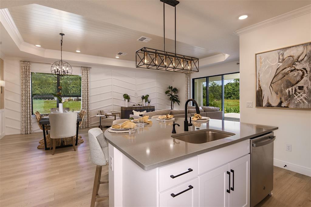 A kitchen island with a sink overlooks an open-concept dining and living area — 11335 STRIPED BASS COURT, NEW PORT RICHEY, FL