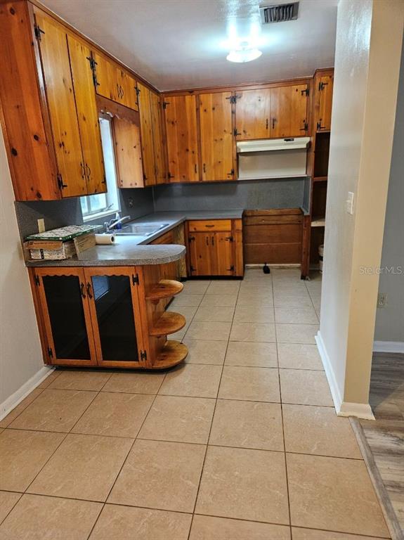 A kitchen features wood cabinets, a gray countertop, and light-colored square floor tiles — 1528 N POWERS DRIVE, ORLANDO, FL