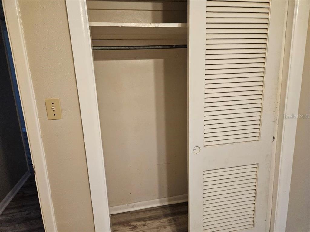 A closet with louvered doors, a shelf, and a hanging rod in a room — 1528 N POWERS DRIVE, ORLANDO, FL