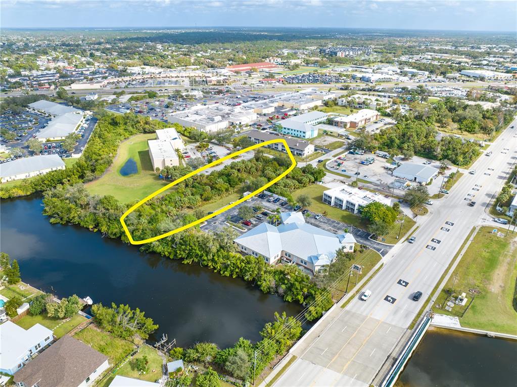 An aerial view shows a wooded lot outlined in yellow next to a canal — 4445 LISTER STREET, PORT CHARLOTTE, FL