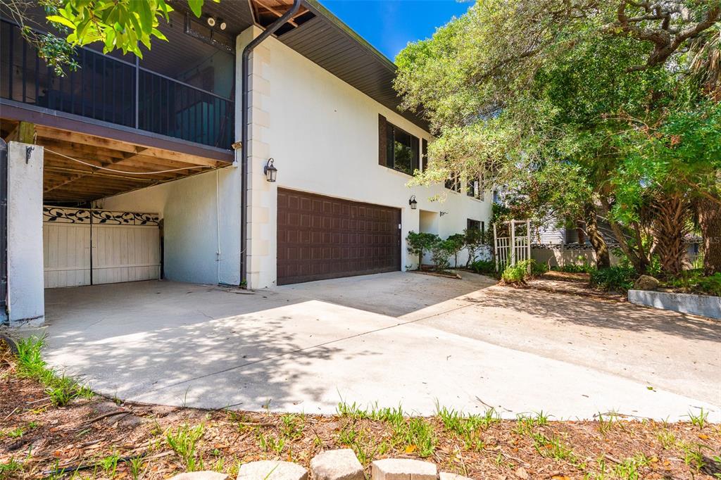 A two-story house features a white exterior, a brown garage door, and a covered carport — 40 CONCORD DRIVE, ORMOND BEACH, FL