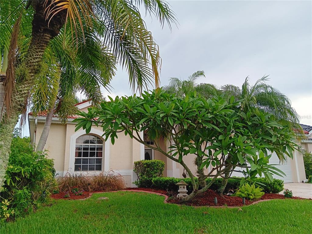 A single-story house with a beige stucco exterior, a tile roof, and lush landscaping — 6828 WINSLOW STREET, SARASOTA, FL