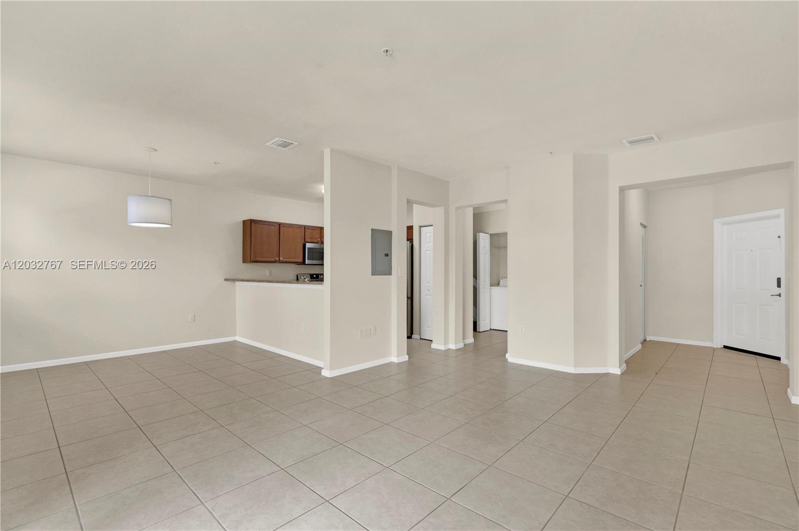An open-concept living area features tile flooring, a kitchen with wood cabinets, and an entryway — 8620 NW 97th Ave # 213, Doral FL 33178, DORAL, FL