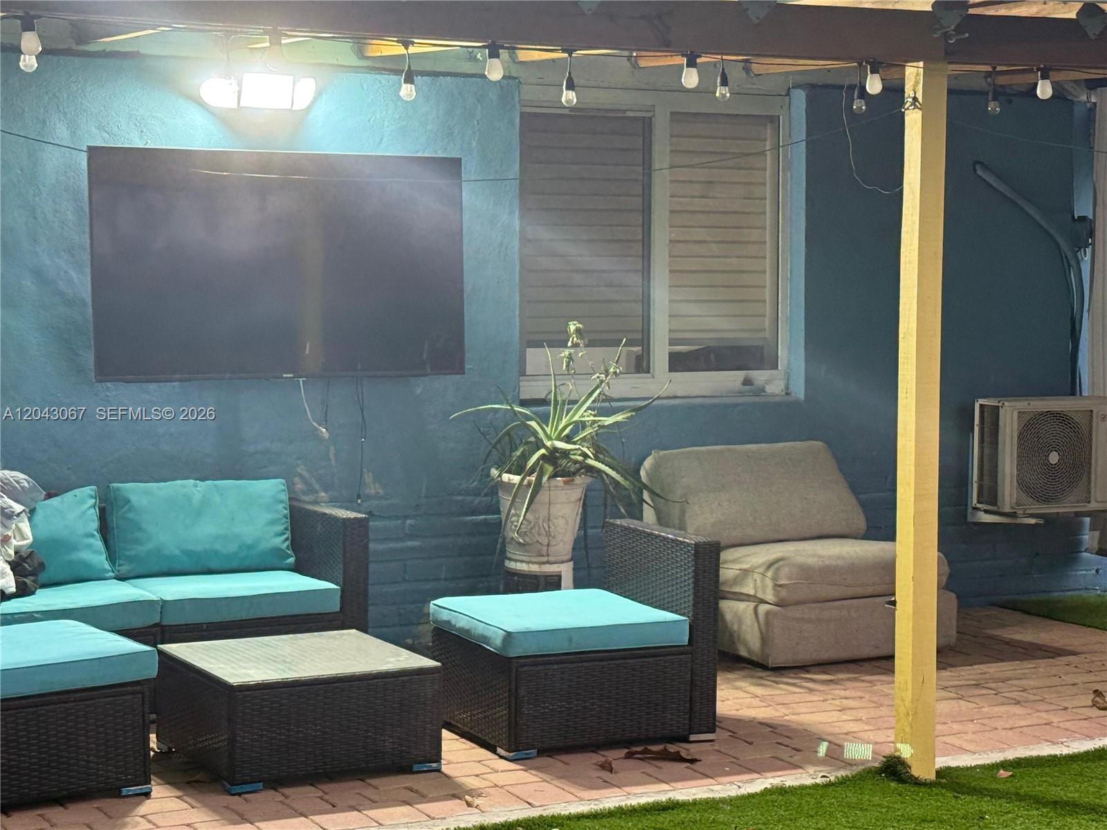 A patio area features a television, outdoor furniture, and a window against a blue wall — 6717 Simms St, Hollywood FL 33024, HOLLYWOOD, FL