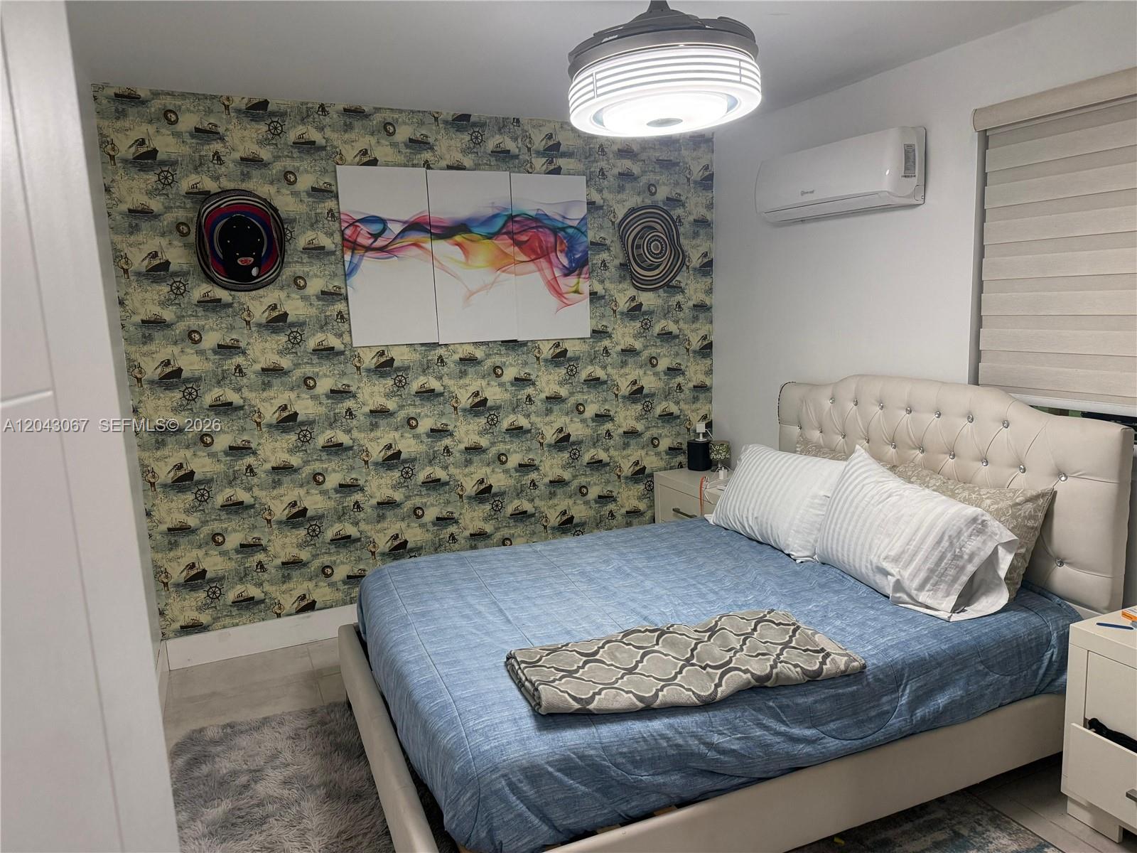 A bedroom features a nautical-themed wallpaper accent wall, a tufted headboard, and a ceiling fan — 6717 Simms St, Hollywood FL 33024, HOLLYWOOD, FL