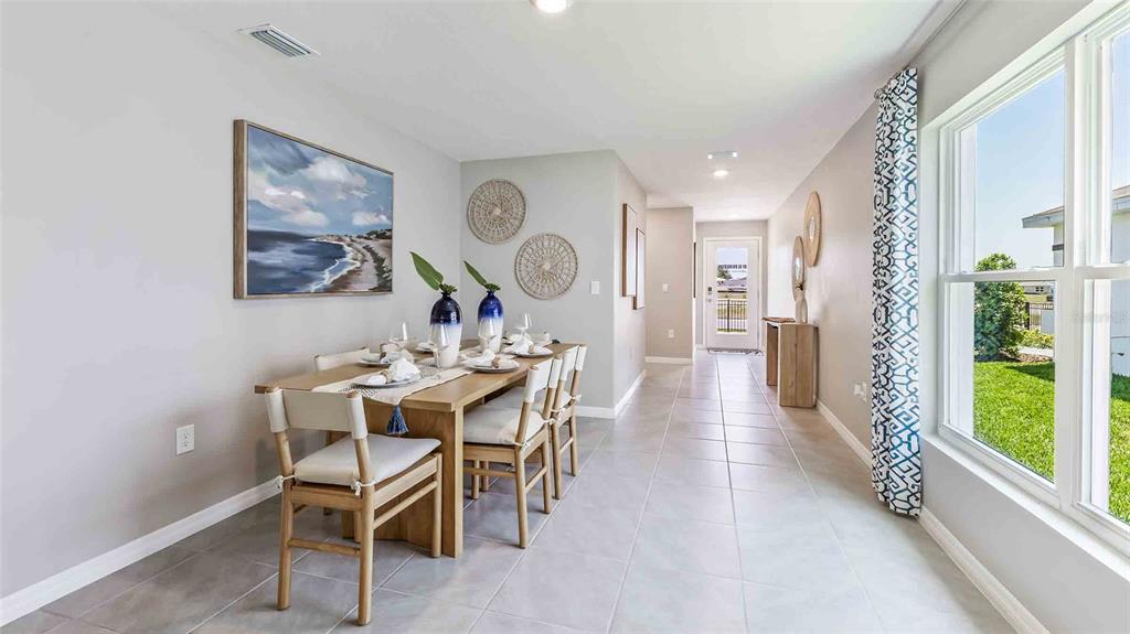 A dining room features a wooden table, light-colored tile floors, and a large window — 7120 FLINT CREEK DRIVE, LAND O LAKES, FL