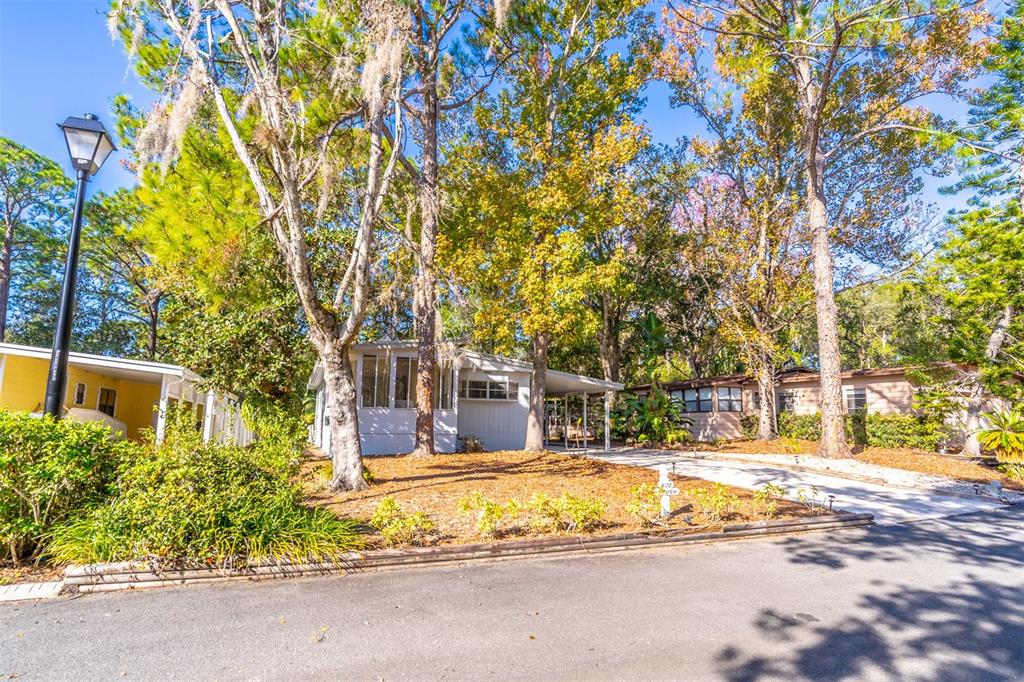 A light-colored mobile home sits on a wooded lot with a paved driveway and carport — 502 TIMBERLANE COURT, LAKE MARY, FL