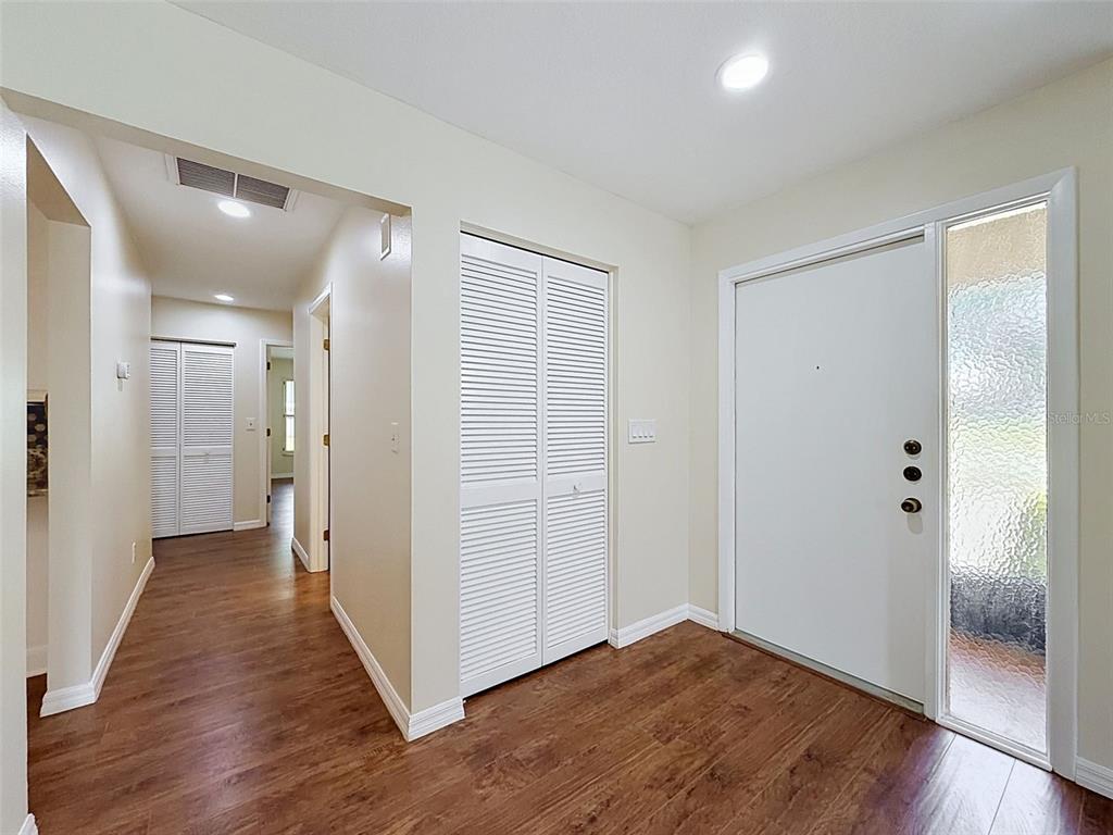 An entryway features wood-look flooring, white louvered closet doors, and a white front door — 3068 E DORCHESTER DRIVE, PALM HARBOR, FL