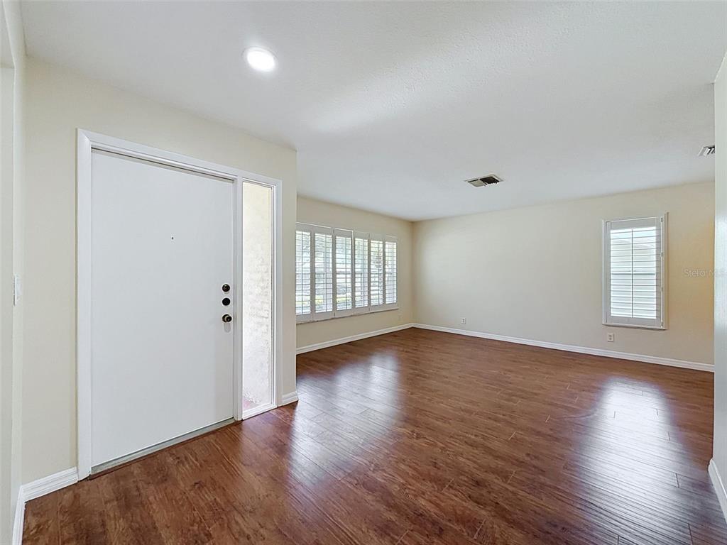 An empty room with wood-look flooring, white walls, and plantation shutters on the windows — 3068 E DORCHESTER DRIVE, PALM HARBOR, FL